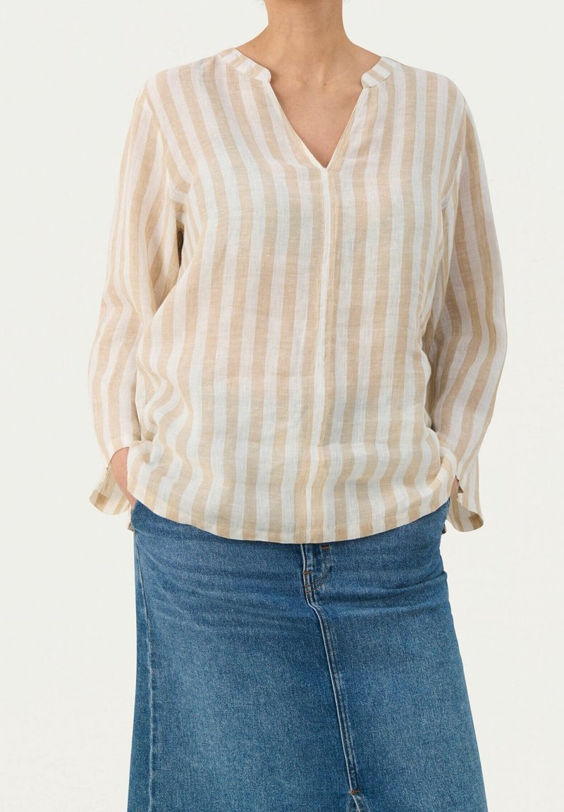 Blusa a righe leggera in crema e beige, con scollo a V, maniche lunghe e vestibilità comoda, abbinata a una gonna di jeans.