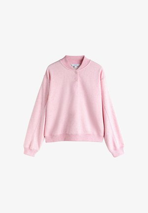 Hele roosa dressipluus pehmest kangast, millel on ümmargune kaelus, kolm nööpi ja soonikkoes mansetid koos õrna täpikese mustriga.