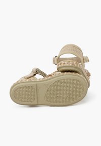 Sandalias tejidas en color beige con suela texturizada, correa trasera ajustable y detalles trenzados decorativos. Diseñadas para la comodidad y la transpirabilidad.