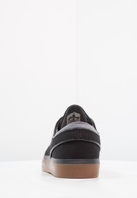 Baskets en textile noir avec un accent en daim gris, finition lisse et semelle en gomme ; présente un profil bas et des détails de couture simples.