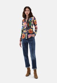 Button-up shirt featuring a multicolored floral pattern, long sleeves, and a classic fit, paired with dark denim jeans and brown ankle boots.