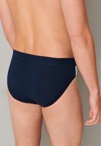 Marineblauwe zwemslips van soepel stof. Beschikt over een effen kleur met een slanke silhouet en een comfortabele tailleband.