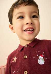 Bordeaux gebreide polo shirt met houten knopen, geborduurde gingerbread man en sneeuwman motieven, met witte sneeuwvlok accenten.