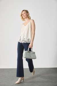 Débardeur en satin beige clair avec dentelle, jeans évasés bleu marine, sac à main gris et talons tressés beiges.