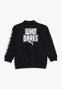 Felpa nera con maniche lunghe, polsini e colletto a coste. Testo grafico bianco "WHO DARES" sulla schiena e sul lato, realizzata in tessuto morbido.