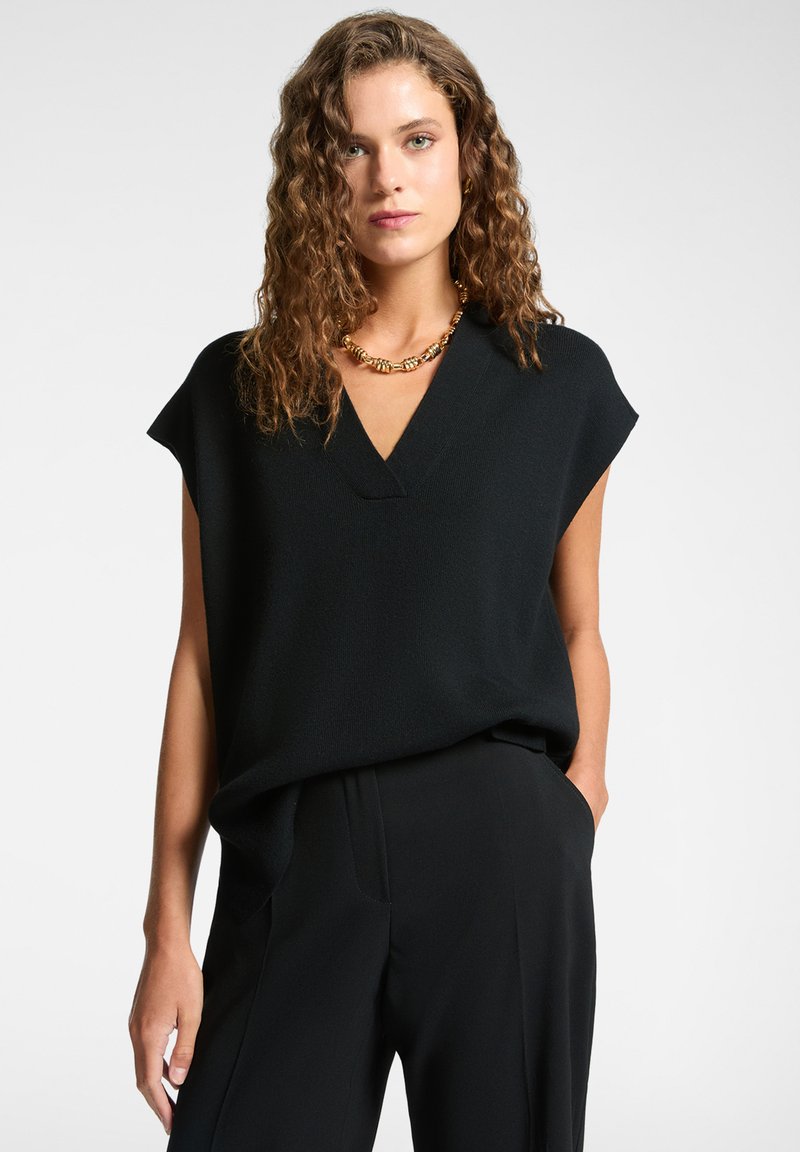 Top negro de manga corta con diseño de escote en V, hecho de tela texturizada, combinado con pantalones negros que cuentan con bolsillos laterales.