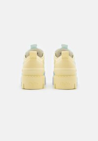 Pastel-colored platform sneakers featuring a mix of yellow and blue textures, with logo detailing on the heel and a padded collar.