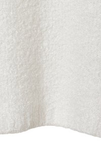 Weißer, strukturierter Stoff mit einer weichen, flauschigen Oberfläche, die einen subtilen Glanz aufweist. Der untere Rand ist leicht gewölbt und zeigt eine Strickstruktur.