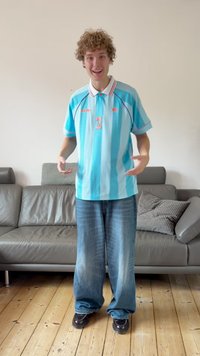 Ανοιχτό μπλε ριγέ πόλο πουκάμισο με γιακά, με λογότυπο και αριθμό 3. Συνδυασμένο με φαρδιά μπλε τζιν παντελόνια και μαύρα παπούτσια.