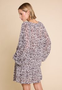 Gjennomsiktig, lett kjole med lange, voluminøse ermer, i et grått og brunt leopardmønster og en plissétrukket skjørt. Jevn tekstur.