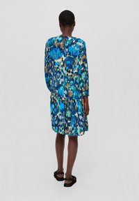 Ein blaues und grünes gemustertes Kleid mit langen Ärmeln, einem gestuften Rock und einem Schlüssellochdetail im Rücken. Hergestellt aus leichtem Stoff.
