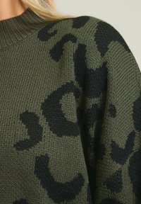 Sweter wykonany na drutach w oliwkowym zielonym kolorze z czarnym wzorem w zwierzęce motywy. Posiada prążkowany okrągły dekolt oraz teksturowaną powierzchnię.