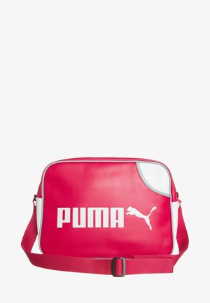 Sac à épaule synthétique rouge avec des accents blancs, présentant un logo sur le devant et une sangle réglable. Texture lisse, forme rectangulaire et fermeture éclair.