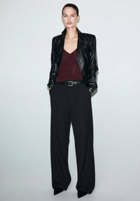 Black leather blazer over a burgundy knit top, paired with black wide-leg trousers and a black belt, set against a light gray background.
