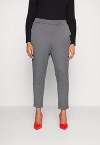 Pantalons en laine grise mélangée avec une coupe fuselée, des ourlets retroussés et une taille plate à l'avant, associés à des escarpins en suede rouge.