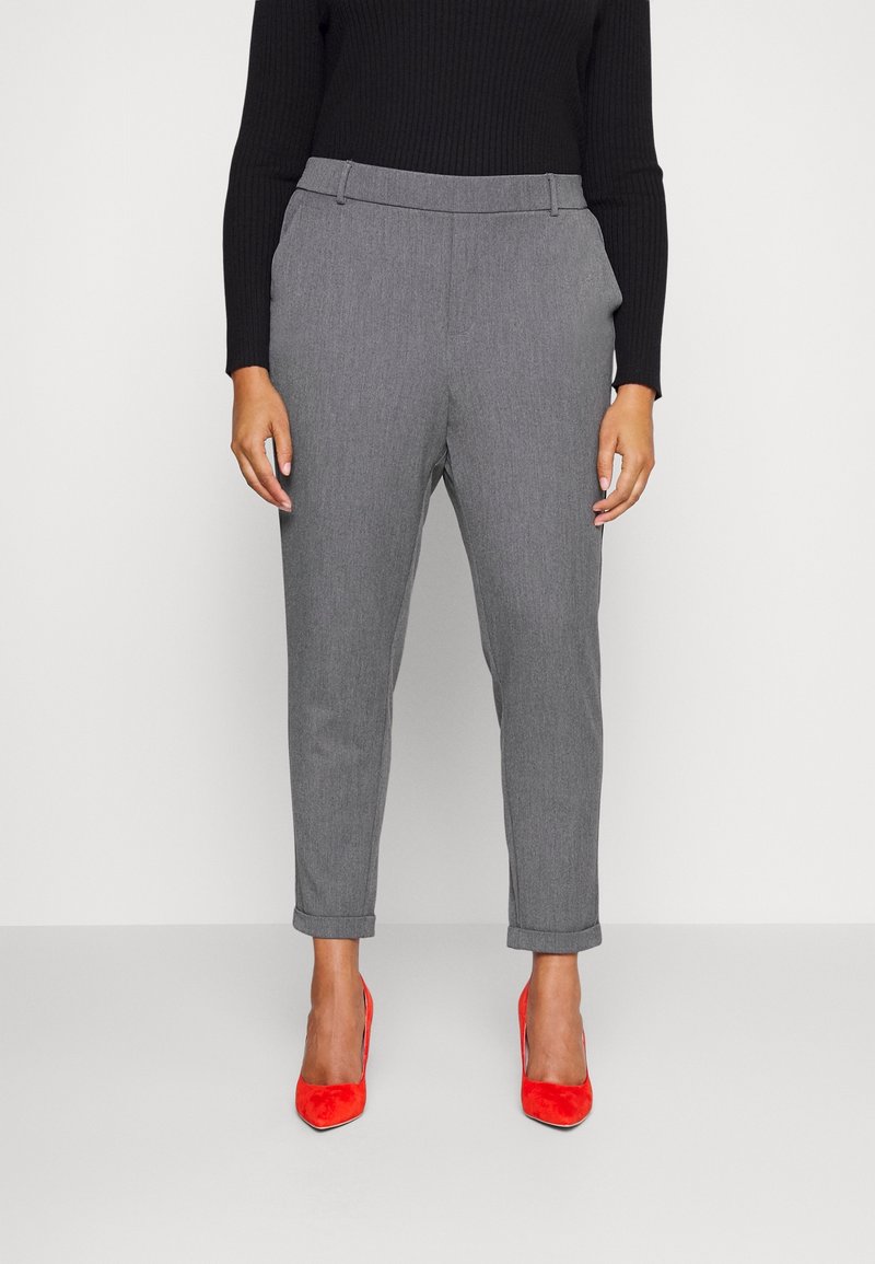 Pantalons en laine grise mélangée avec une coupe fuselée, des ourlets retroussés et une taille plate à l'avant, associés à des escarpins en suede rouge.