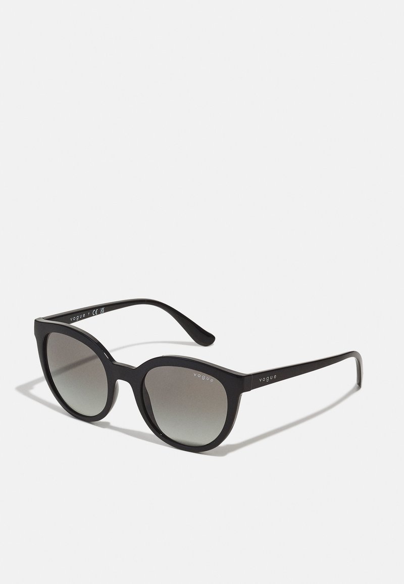 Ochelari de soare din plastic negru, cu o formă îndrăzneață, tip cat-eye și lentile gradient. Prezintă numele brandului "Vogue" în argintiu pe braț.