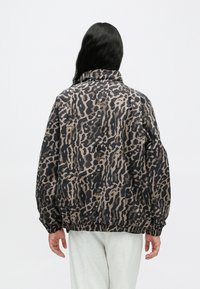 Μπουφάν με λεοπάρ εκτύπωση σε μαύρο και μπεζ χρώμα, με ψηλό γιακά, ελαστικά μανσέτες και τελείωμα. Κατασκευασμένο από ελαφρύ ύφασμα, με άνετη εφαρμογή.