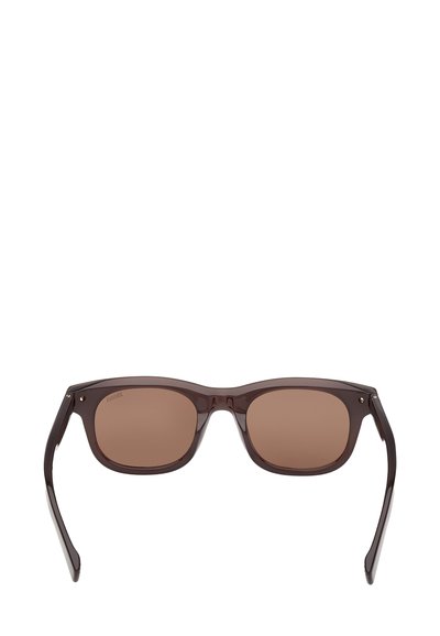 Brązowe plastikowe okulary przeciwsłoneczne z kwadratowymi soczewkami, smukłą oprawą i minimalistycznymi elementami metalowymi. Soczewki są brązowo przyciemniane, co nadaje im nowoczesny design.