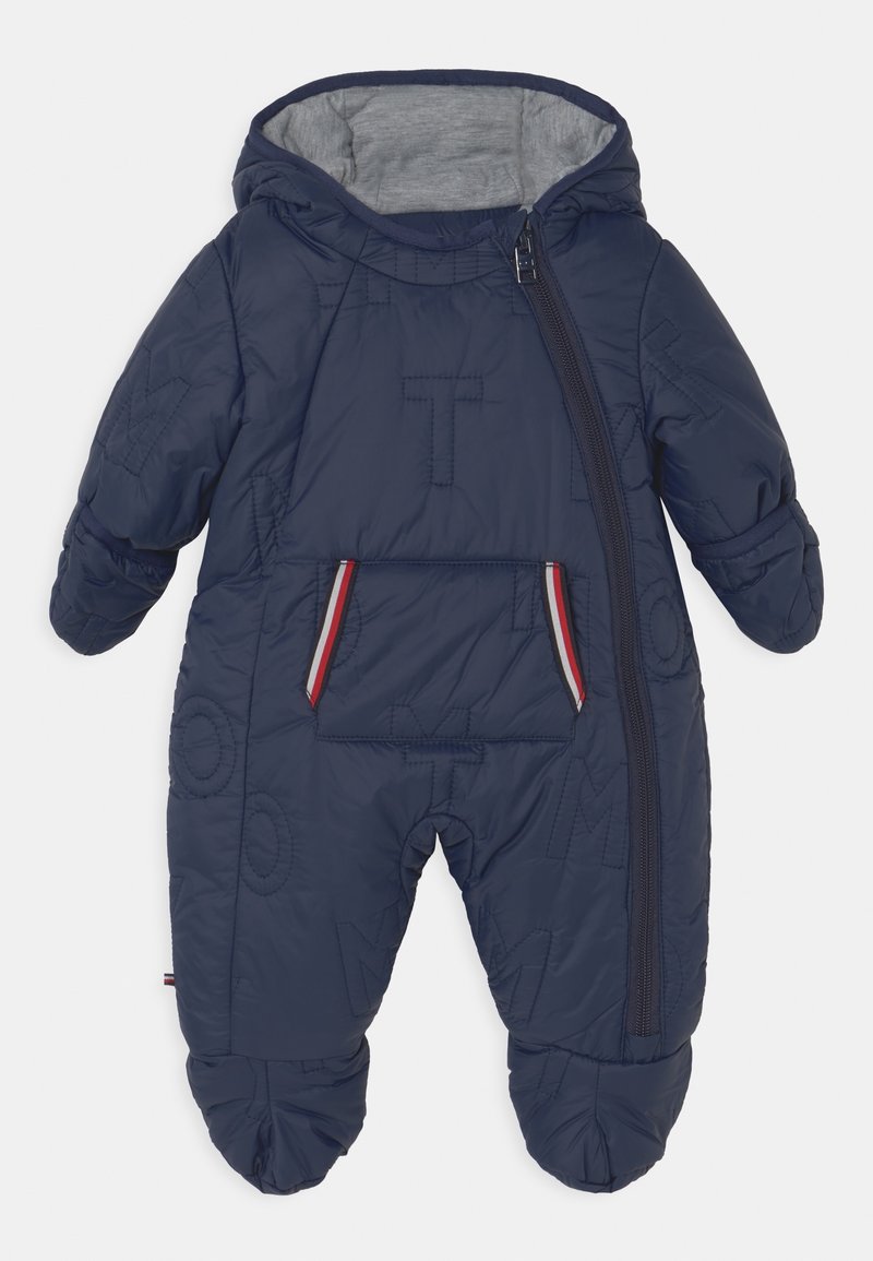 Combinaison de neige matelassée bleu marine pour bébé avec capuche, fermeture éclair diagonale à l'avant, lettres matelassées et une poche avant avec un liseré rouge et blanc.