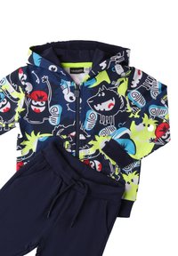 Navy Kapuzenpullover mit mehrfarbigen Monster-Drucken, Reißverschluss und einer Jogginghose aus passendem navyfarbigen Stoff. Aus einem weichen Baumwollmischgewebe.