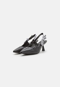 Dei décolleté slingback in vernice nera con punta affusolata e tacco medio a blocco. Presentano una fascia bianca a contrasto con il logo alla caviglia.