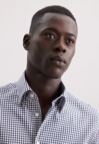 Overhemd met een marineblauw en wit ruitpatroon, voorzien van knopen en een gestructureerde kraag, gemaakt van lichtgewicht katoenen stof.