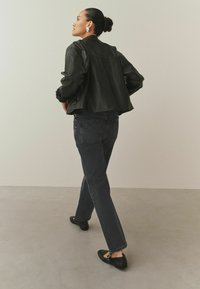 Čierna kožená bunda, tmavé džínsové nohavice, čierne baleríny s kovovými ozdobami. Jednoduchý dizajn, pohodlný strih a hladká textúra.