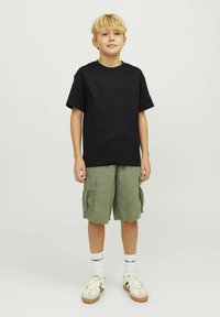 Svart bomullströja, gröna cargo-shorts med sidfickor, vita korta strumpor och beige sneakers med bruna detaljer. Enkelt, avslappnat outfit.