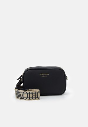 Sac bandoulière rectangulaire en cuir noir avec logo doré Emporio Armani Milano 1981 et sangle en tissu beige marqué.