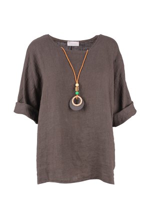 Braune locker sitzende Leinenbluse mit hochgekrempelten kurzen Ärmeln und einer Halskette mit rundem schwarz-beigem Anhänger an einer orangen Schnur.