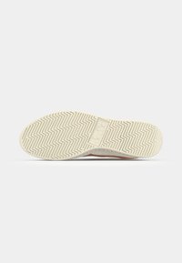 Rubber shoe sole with a herringbone pattern, featuring a light beige color and a logo on the side. Textured for grip and durability.