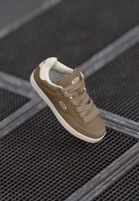 Brown leather sneaker with beige accents, round toe, padded collar, and lace-up design. Features logo detail on the side and textured sole.