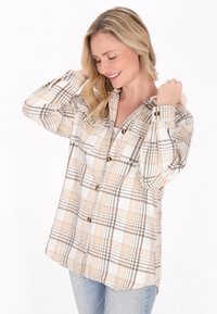 Beige och vit rutad flanellskjorta med bruna accenter, knäppning fram, långa ärmar och sprund i fållen. Mjuk textur.