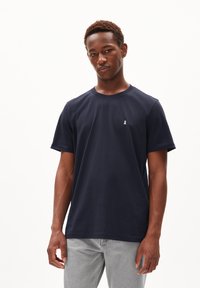 T-shirt en coton bleu marine avec des manches courtes, col rond, et un petit logo blanc sur la poitrine. Design uni sans motifs ni accents.