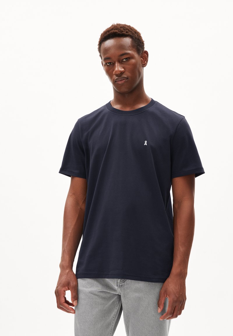 T-shirt en coton bleu marine avec des manches courtes, col rond, et un petit logo blanc sur la poitrine. Design uni sans motifs ni accents.