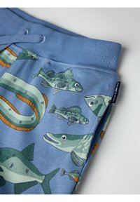 Blauwe stoffen broek met een vispatroon in verschillende tinten groen en oranje. Voorzien van een geribde tailleband en een trekkoordsluiting.