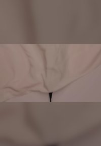 Ljust beige filt med en texturerad yta, samlad nertill där en svart dragkedja är synlig. Skrynkligt tygutseende.