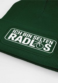 Dark green knit beanie featuring a textured finish and a white patch with the text "ICH BIN SELTEN RADLÖS," conveying a bicycle theme.