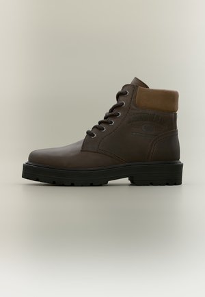 Bottine en cuir marron à lacets, avec un col rembourré et une épaisse semelle noire crantée, présentée de profil sur un fond uni.