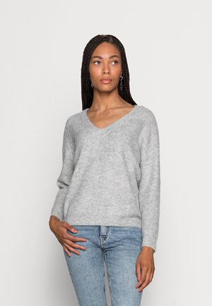 Maglione grigio lavorato a maglia con scollatura a V, maniche lunghe e una consistenza morbida. Abbinato a jeans blu, con una vestibilità rilassata e informale.