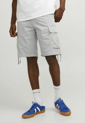 Lys grå cargo shorts med sidelommer, justerbare snore og løs pasform, parret med blå sneakers og hvide sokker med tekst.