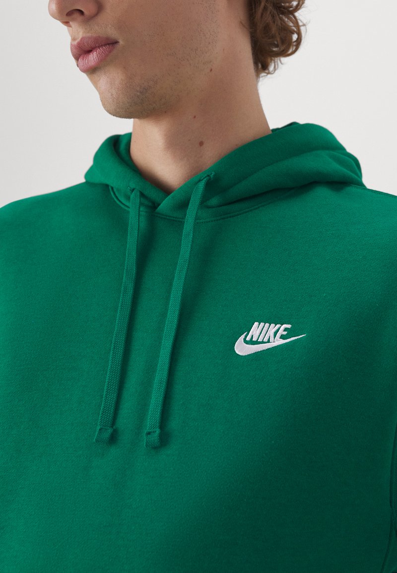 Sudadera verde de Nike hecha de tela suave, con un bolsillo canguro frontal, cordones ajustables y un logo blanco en el pecho.