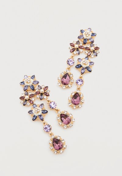 Κρεμαστά σκουλαρίκια σε χρυσαφί απόχρωση με μωβ, λιλά και διαφανή κρύσταλλα διατεταγμένα σε σχήματα λουλουδιών και σταγόνων.