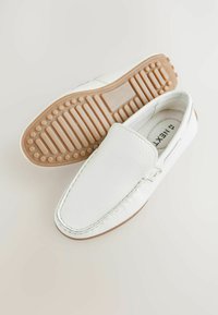 Biele kožené slip-on topánky s textúrovaným povrchom, okrúhlou špičkou a gumovou podrážkou so vzorovaným gripom pre lepšiu trakciu.