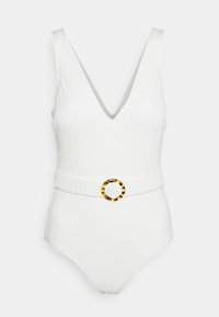 Maillot de bain blanc en une pièce avec un décolleté en V, un tissu texturé et une ceinture beige ornée d'une boucle en écaille de tortue ronde.