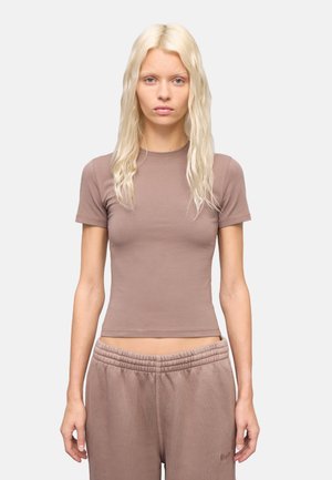 Camiseta ajustada de manga corta marrón con cuello redondo, hecha de tela suave, combinada con pantalones de chándal relajados a juego que tienen una cinturilla elástica.