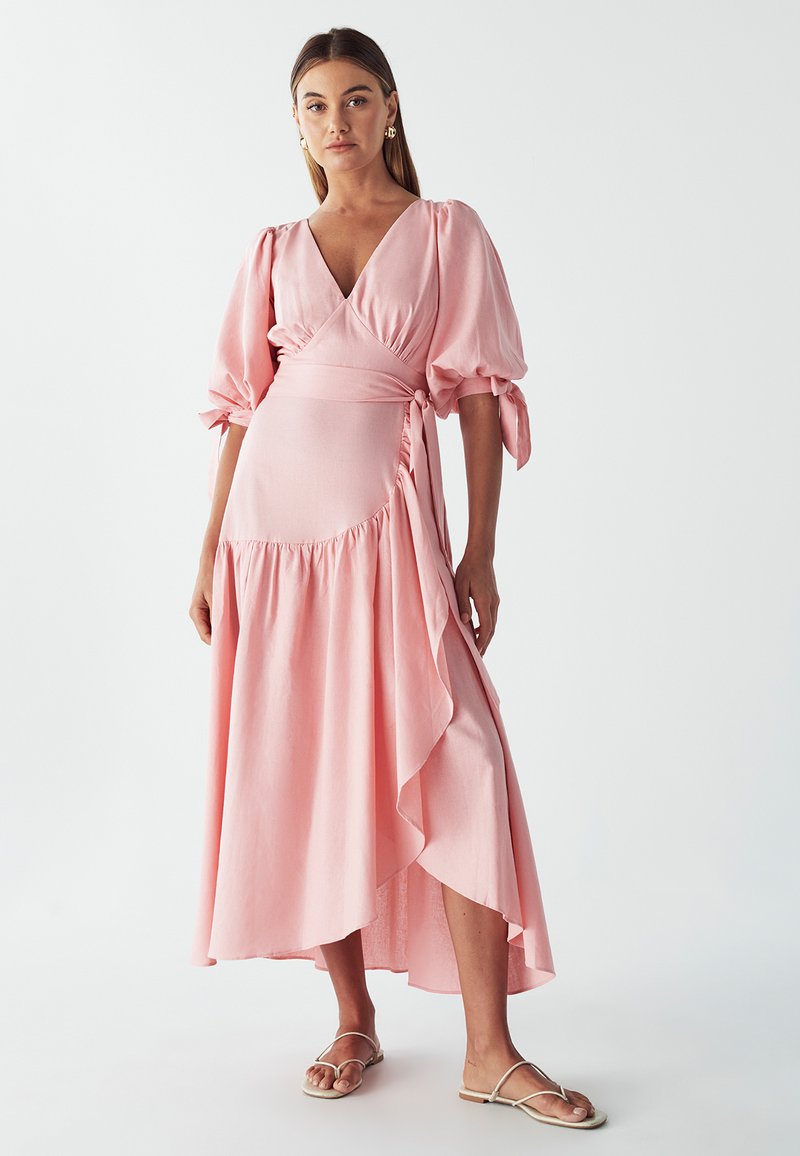 Pink wrap dress with puff sleeves, ruffled hem, and a side tie detail. Made of lightweight fabric, featuring a deep V-neckline.