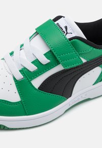 Roheline ja must nahkne tennisekeng valgete lace'ide ja velcro rihmaga. Omab augulist varbatüübi ja tekstuurseid külgmisi aktsente, mis tagavad haarde.