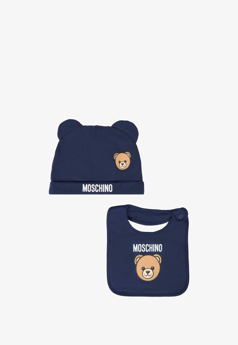Gorro de algodón azul marino con orejas de oso y logo; el babero a juego presenta un gráfico de oso y el logo; ambos cuentan con una textura suave y un diseño informal.